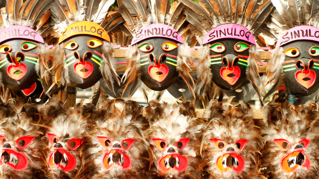 Chicken feather-adorned masks with vibrant, colorful decorations displayed for sale at a stall during the Sinulog Festival in Cebu City, Philippines.