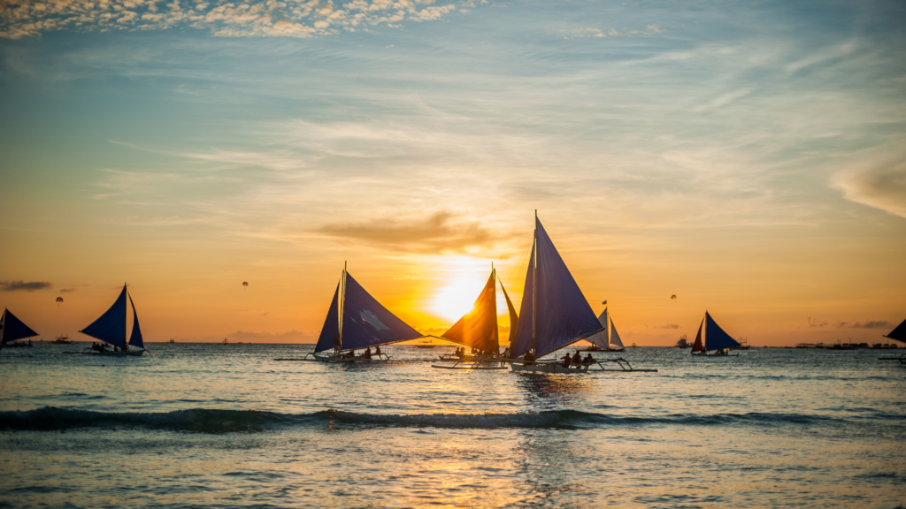 Sailboats gliding across the water at sunset on Boracay Island. Best Time to Visit the Philippines