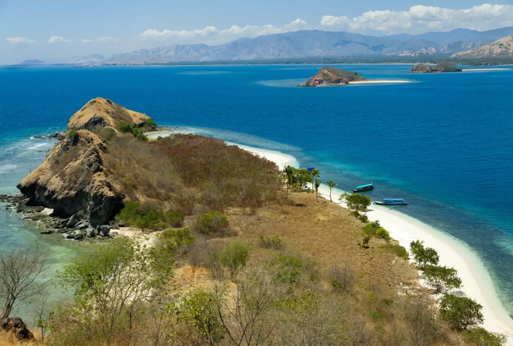 A serene blue sky dotted with fluffy white clouds above the stunning Cristal Clear Water lagoon in Riung, Flores, Indonesia.