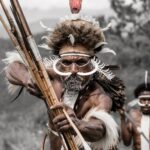 Black and white photograph featuring a Dani Warriors man, skillfully holding a bow and arrow, representing tribal culture.