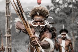 Black and white photograph featuring a Dani Warriors man, skillfully holding a bow and arrow, representing tribal culture.