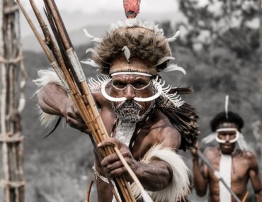 Black and white photograph featuring a Dani Warriors man, skillfully holding a bow and arrow, representing tribal culture.