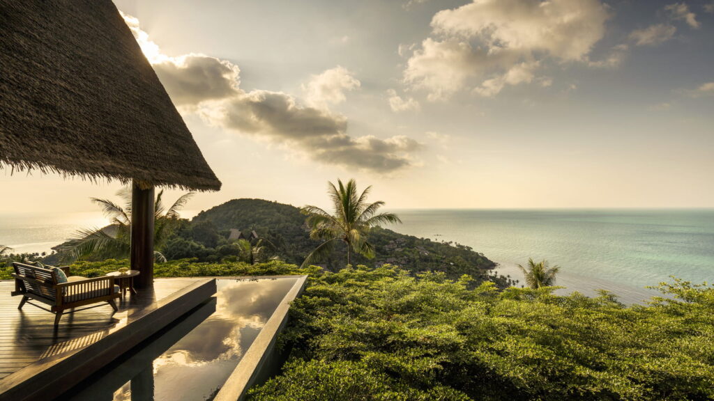 Relax under a thatched roof by the pool, with breathtaking ocean views at the luxurious Four Seasons Resort Koh Samui.