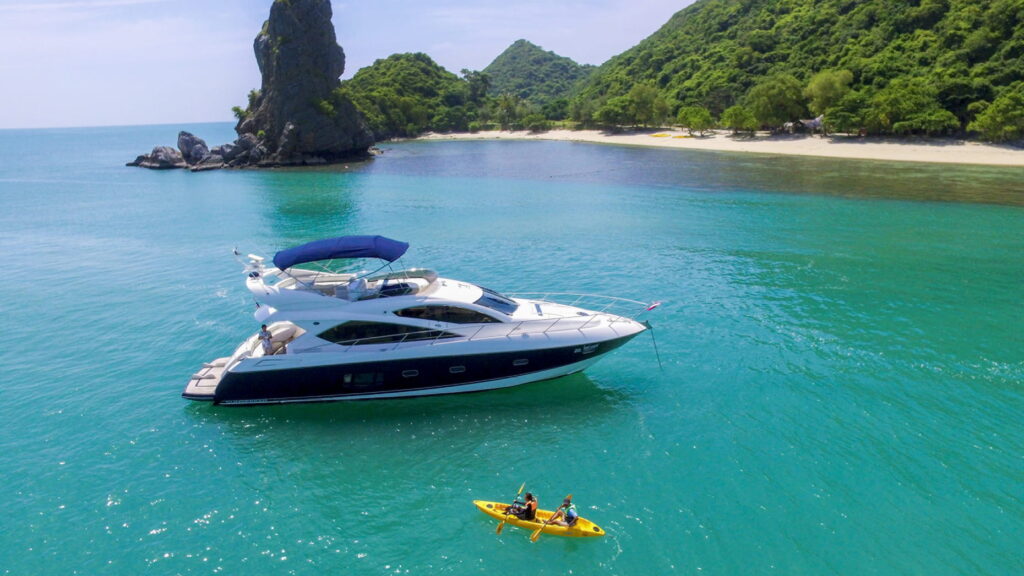 A charter boat glides through the ocean, close to a rocky island in Ang Thong National Marine Park.