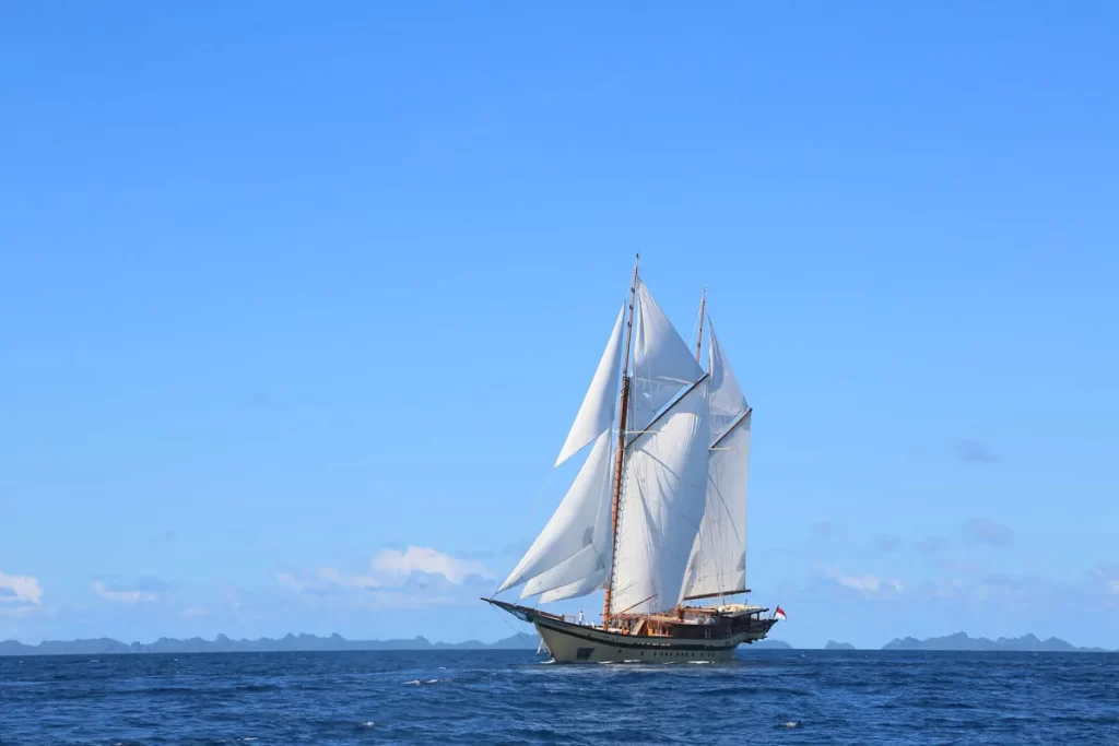 A luxurious sailboat gliding gracefully across the sparkling ocean waves under a clear blue sky.