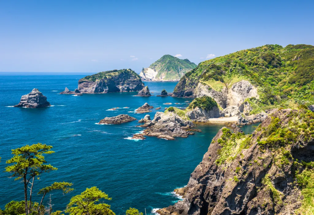 Stunning coastal scenery on the Izu Peninsula for luxury Japan travel, showcasing rugged cliffs and turquoise water under a blue sky. Perfect for Japan holidays designed by a specialist Japan DMC.