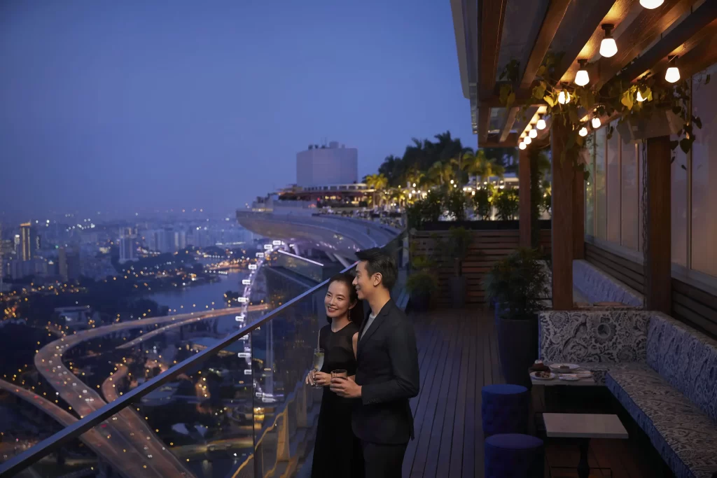  A couple enjoys a romantic moment on a balcony, gazing at the stunning skyline of Marina Bay Sands, Singapore.