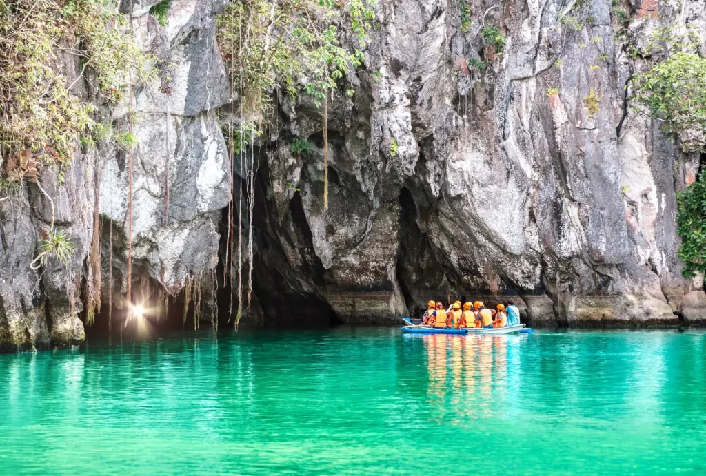 A group of adventurers in a boat exploring the stunning Puerto Princesa Underground River near a captivating cave.