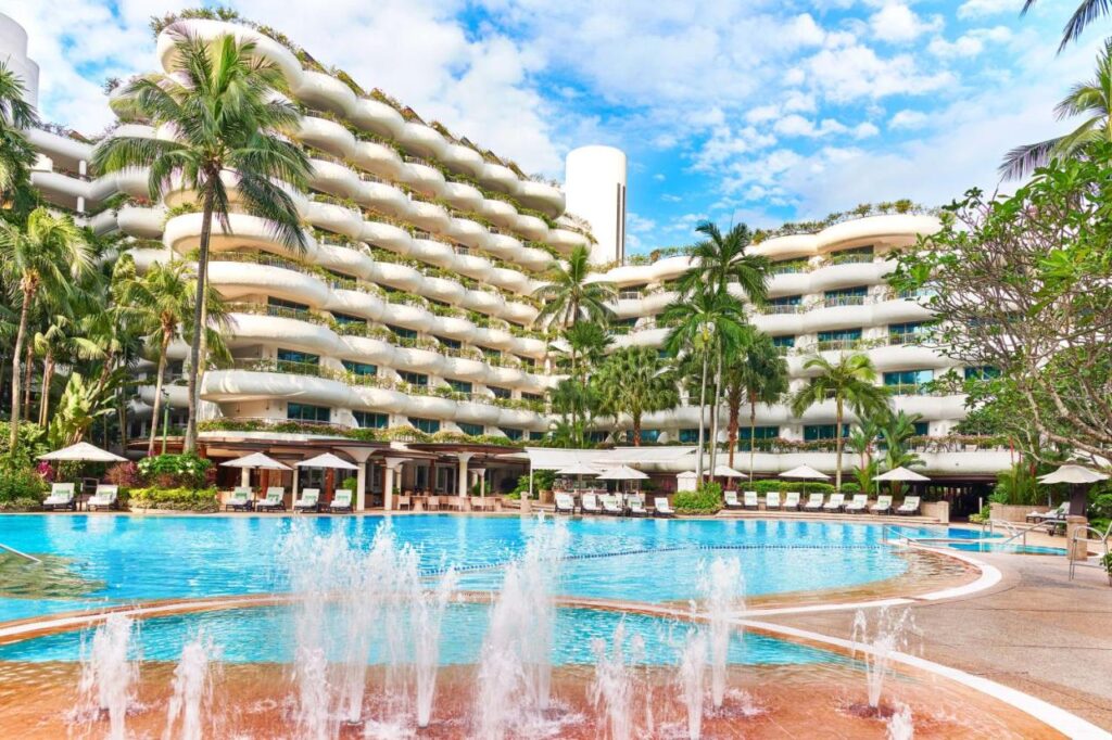 A serene hotel pool at Shangri-La Singapore, framed by lush palm trees, inviting relaxation and tranquility.