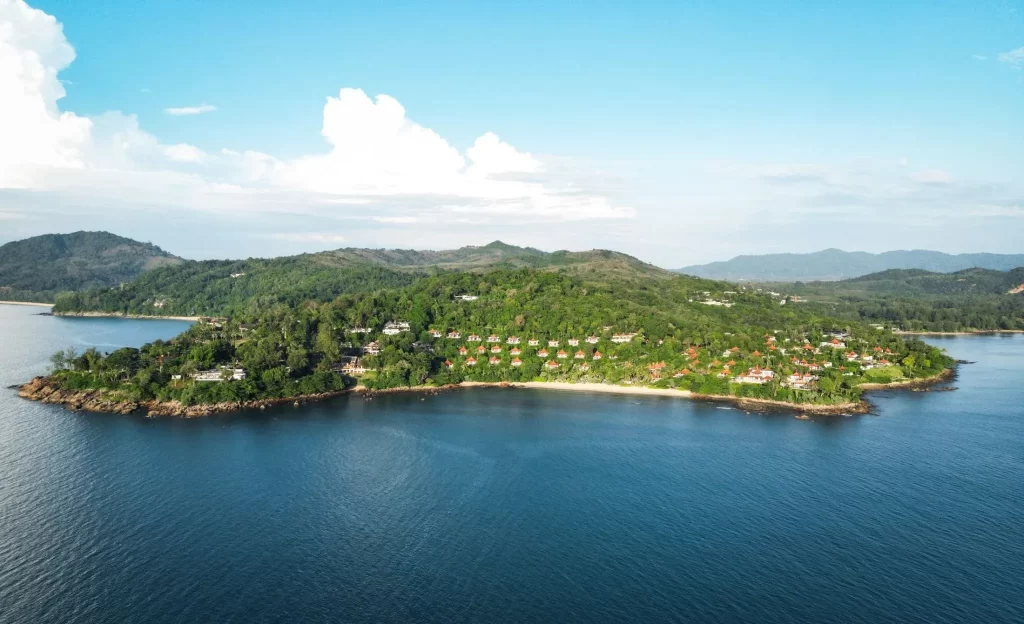 Aerial view of a luxury resort nestled in tropical forest on a private peninsula in phuket, Thailand, surrounded by calm blue Andaman Sea waters
