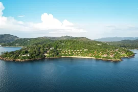 Aerial view of a luxury resort nestled in tropical forest on a private peninsula in phuket, Thailand, surrounded by calm blue Andaman Sea waters