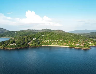 Aerial view of a luxury resort nestled in tropical forest on a private peninsula in phuket, Thailand, surrounded by calm blue Andaman Sea waters