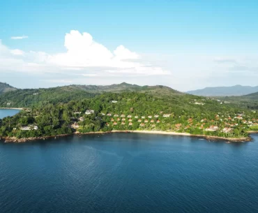 Aerial view of a luxury resort nestled in tropical forest on a private peninsula in phuket, Thailand, surrounded by calm blue Andaman Sea waters