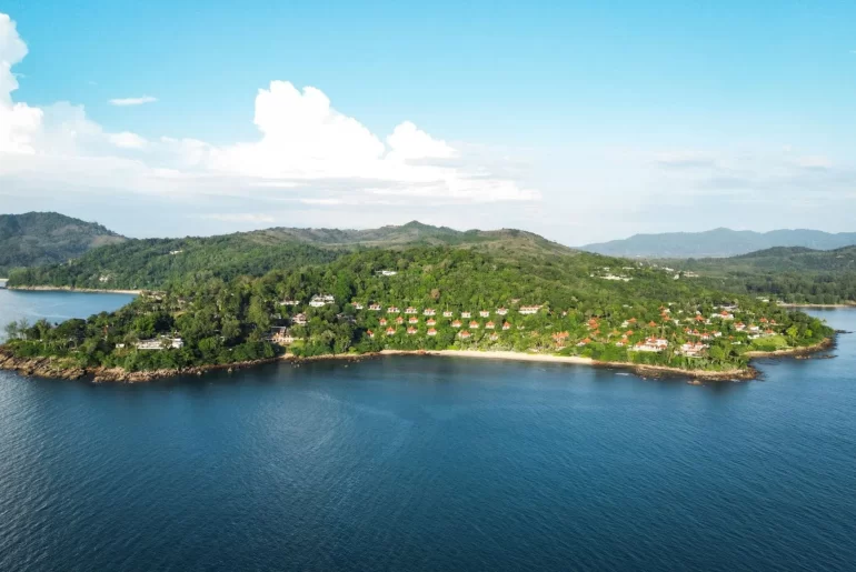 Aerial view of a luxury resort nestled in tropical forest on a private peninsula in phuket, Thailand, surrounded by calm blue Andaman Sea waters