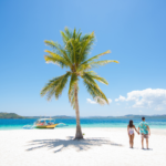 Couple on a tropical beach with blue water and palm tree ( Coron, Philippines)