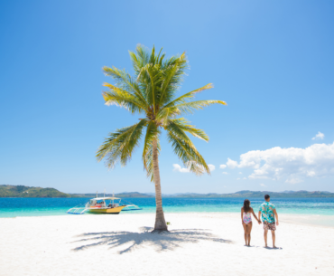 Couple on a tropical beach with blue water and palm tree ( Coron, Philippines)