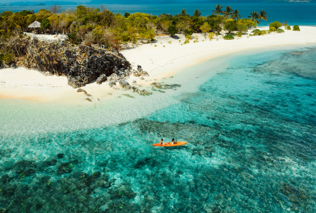 couple kayaking in tropical beach blue water and white sand in  Coron, Philippines.