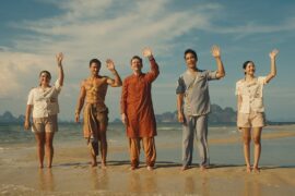 5. People standing on the beach, waving their hands in excitement, enjoying a sunny day by the ocean.