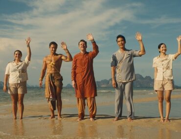 5. People standing on the beach, waving their hands in excitement, enjoying a sunny day by the ocean.