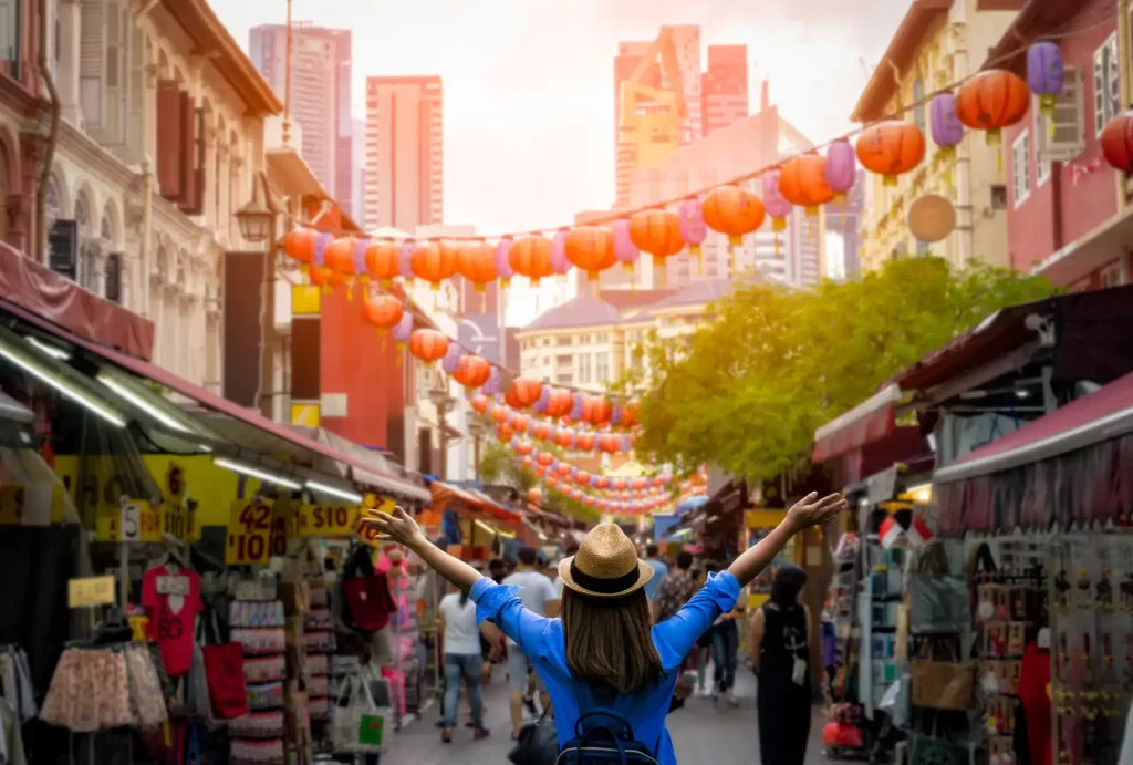 Young woman traveler with backpack and hat traveling into Chinatown at singapore city