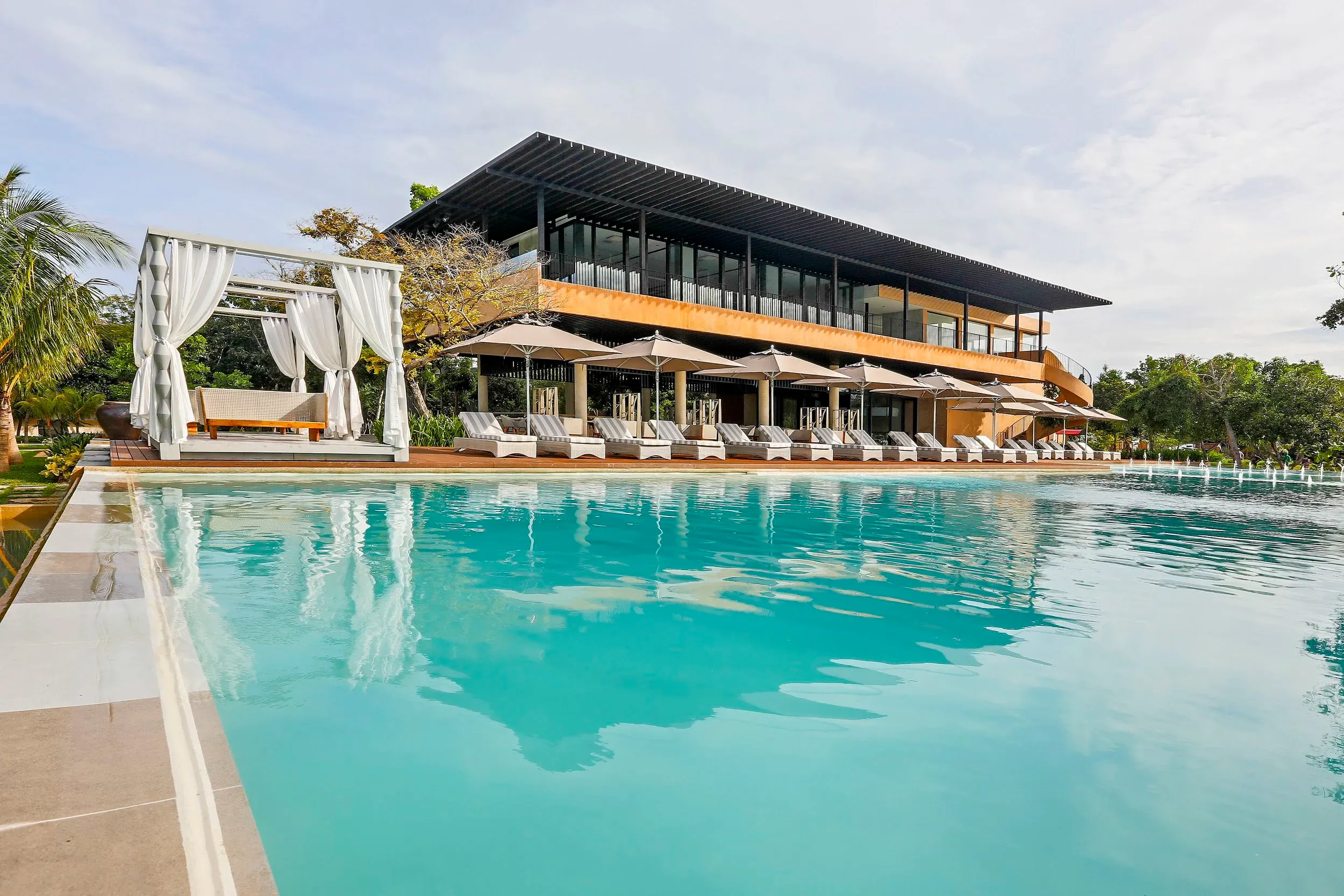 Large infinity swimming pool surrounded by lounge chairs, daybeds, and umbrellas at Amorita Resort in Panglao, Bohol.