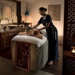 A woman receives a relaxing back massage at the luxurious Anantara Layan Phuket Resort spa. This image highlights premium wellness experiences for travelers