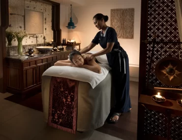A woman receives a relaxing back massage at the luxurious Anantara Layan Phuket Resort spa. This image highlights premium wellness experiences for travelers