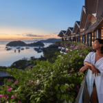 A woman stands on a hotel balcony at a resort, gazing out at the beautiful ocean, soaking in the tranquil surroundings.