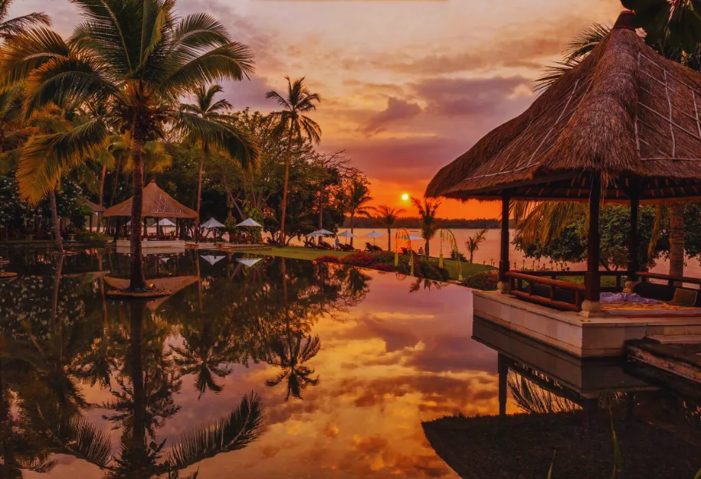 Private cabana and infinity pool reflecting a vibrant sunset at a luxury beach resort. Experience bespoke Indonesia holidays and premium Indonesia travel designed by our expert DMC.