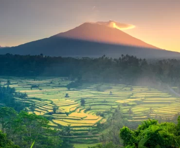 Sunrise over terraced rice fields beneath Mount Agung, Bali's sacred volcano, viewed from the quiet eastern highlands — the Bali that exists beyond Seminyak and Ubud's well-worn trails