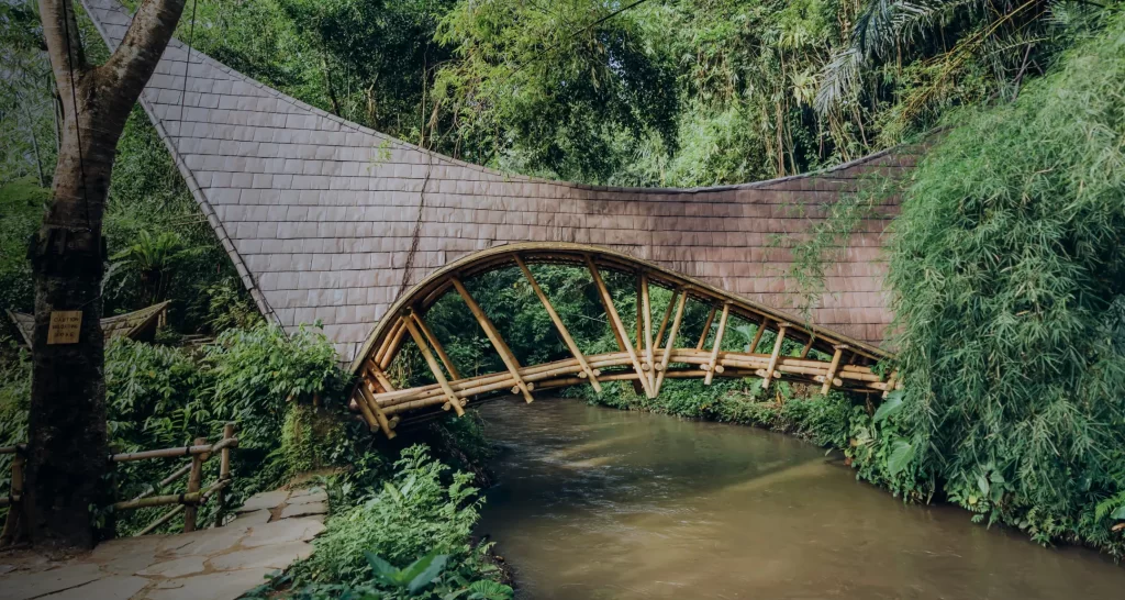 The handcrafted bamboo bridge spanning the river gorge at Bambu Indah, Ubud — a sustainably built boutique retreat where Balinese craftsmanship and jungle immersion define every detail