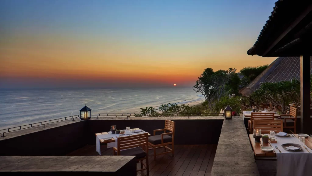 Sunset dinner on the clifftop terrace at Il Ristorante - Luca Fantin, Bvlgari Resort Bali, with candlelit tables overlooking the Indian Ocean as the sun drops below the horizon — one of the great restaurant views in Asia