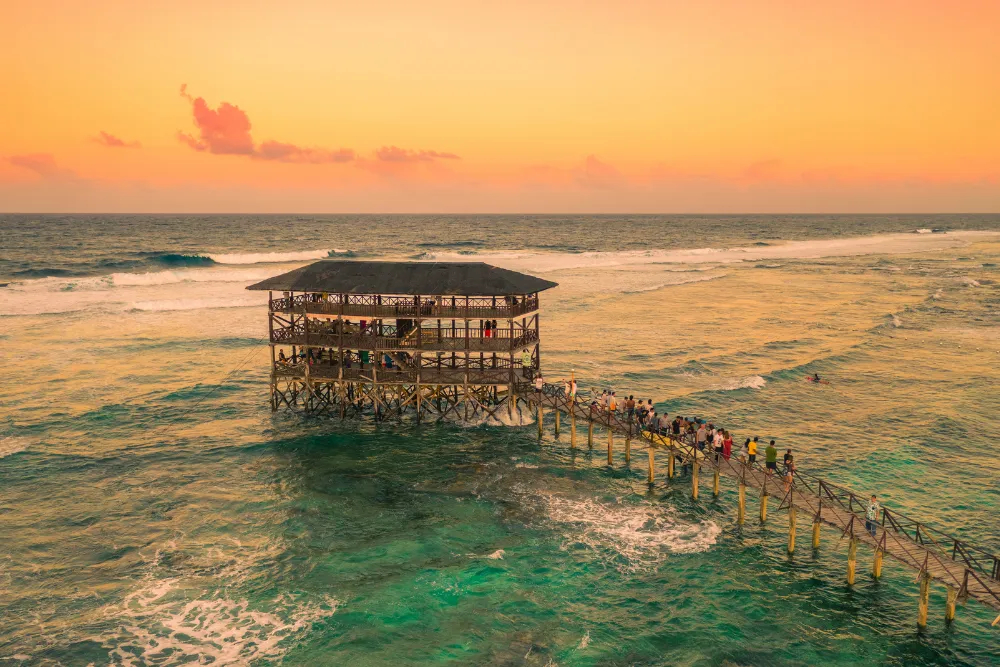 Aerial view of Cloud 9's iconic wooden surf boardwalk in Siargao, Philippines, at golden sunset.