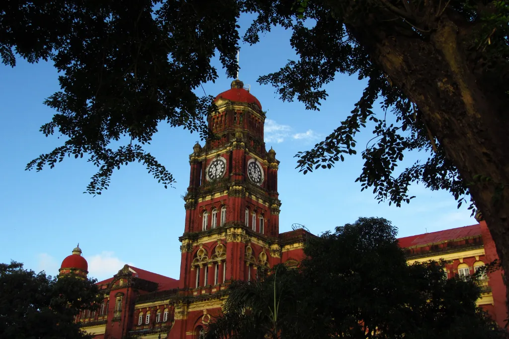 Red-brick colonial High Court clock tower framed by trees in Yangon, Myanmar