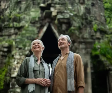 Mature couple admiring a jungle-covered stone gate at Angkor Thom, Cambodia. Photo courtesy of Park Hyatt Siem Reap