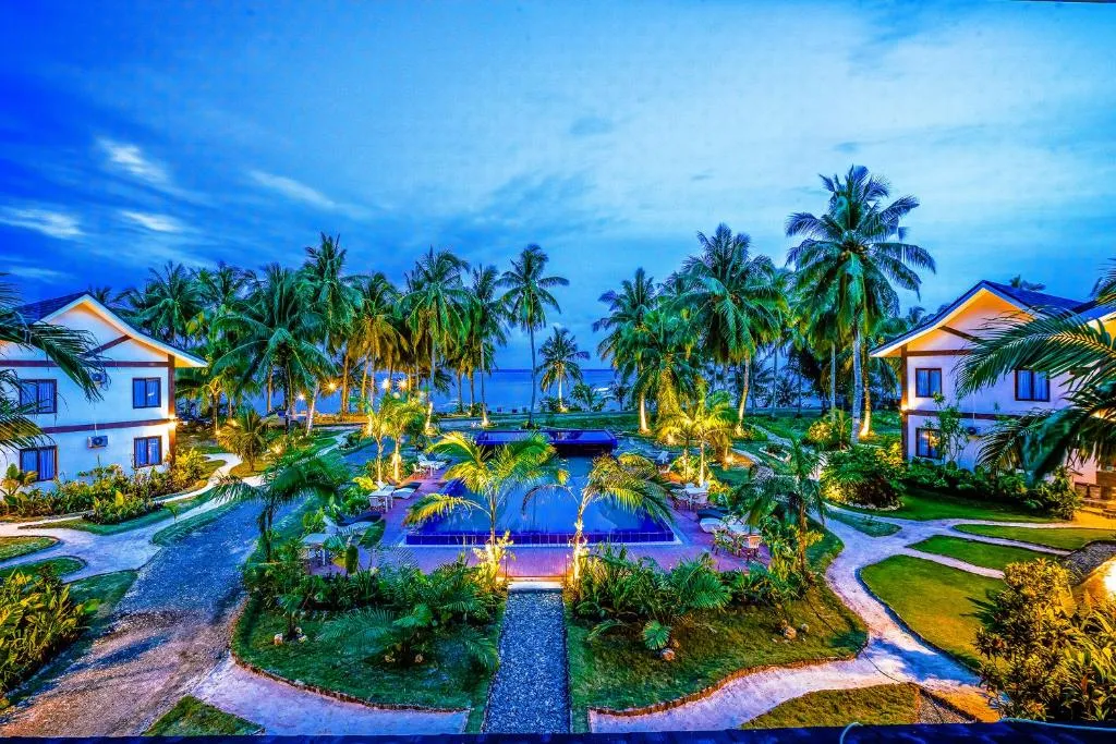 Aerial twilight view of Retreat Siargao's pool and villa suites among the coconut groves of Malinao.
