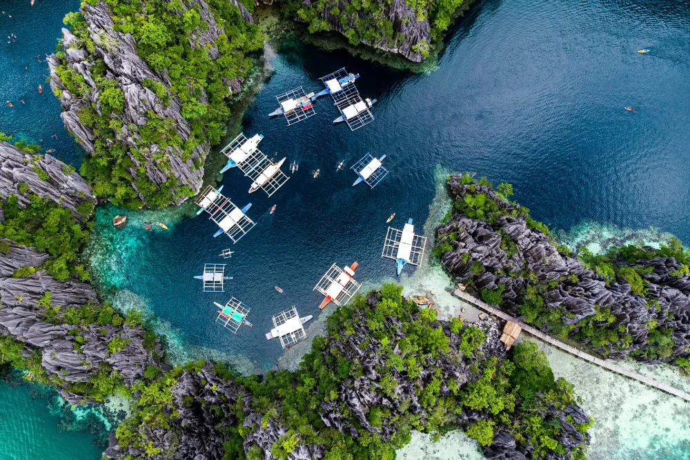 Aerial view of luxury outrigger boats in Kayangan Lake, Coron, curated by a premier Philippines DMC for a bespoke Palawan island hopping tour.