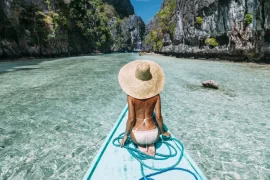 A luxury traveler on a private traditional boat entering Big Lagoon, El Nido. Tailored Palawan island hopping itineraries provided by a leading Philippines DMC.