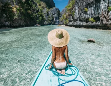 A luxury traveler on a private traditional boat entering Big Lagoon, El Nido. Tailored Palawan island hopping itineraries provided by a leading Philippines DMC.