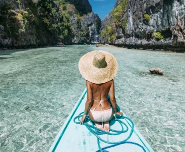 A luxury traveler on a private traditional boat entering Big Lagoon, El Nido. Tailored Palawan island hopping itineraries provided by a leading Philippines DMC.