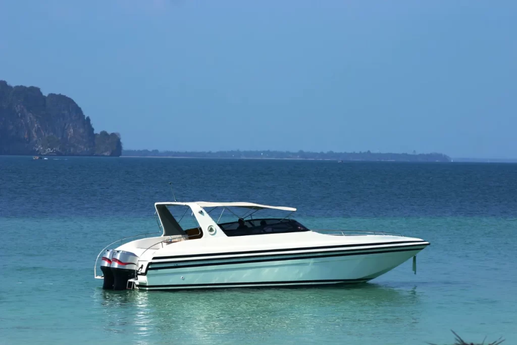 Luxury private speedboat anchored in calm turquoise waters with dramatic limestone karst islands in the background, available for island-hopping transfers and Myanmar tours — Discovery DMC