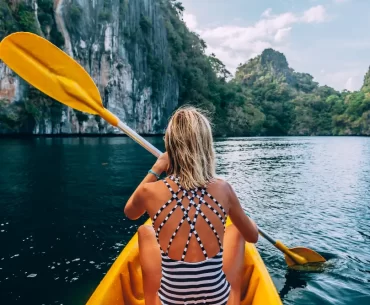 A traveler enjoying a bespoke kayaking journey through the limestone lagoons of Palawan, Philippines.