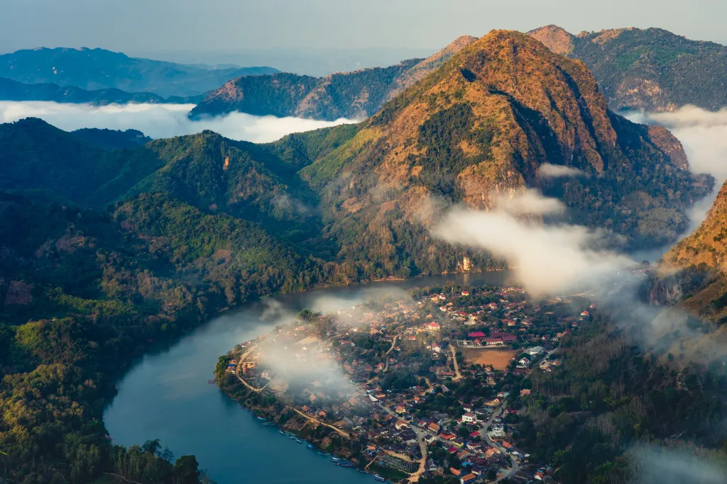Nong Khiaw village on the Nam Ou River beneath misty karst mountains, northern Laos