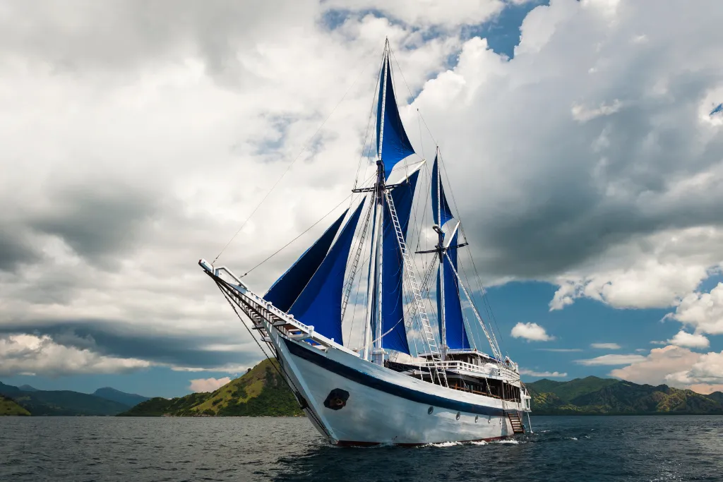 Traditional phinisi sailing yacht with blue sails cruising Komodo National Park, Indonesia
