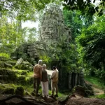 Couple with a private guide at a jungle-covered stone face gate of Angkor Thom, Cambodia. Photo courtesy of Park Hyatt Siem Reap
