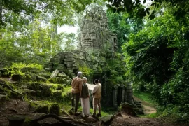 Couple with a private guide at a jungle-covered stone face gate of Angkor Thom, Cambodia. Photo courtesy of Park Hyatt Siem Reap