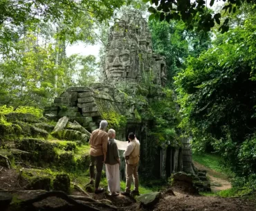 Couple with a private guide at a jungle-covered stone face gate of Angkor Thom, Cambodia. Photo courtesy of Park Hyatt Siem Reap