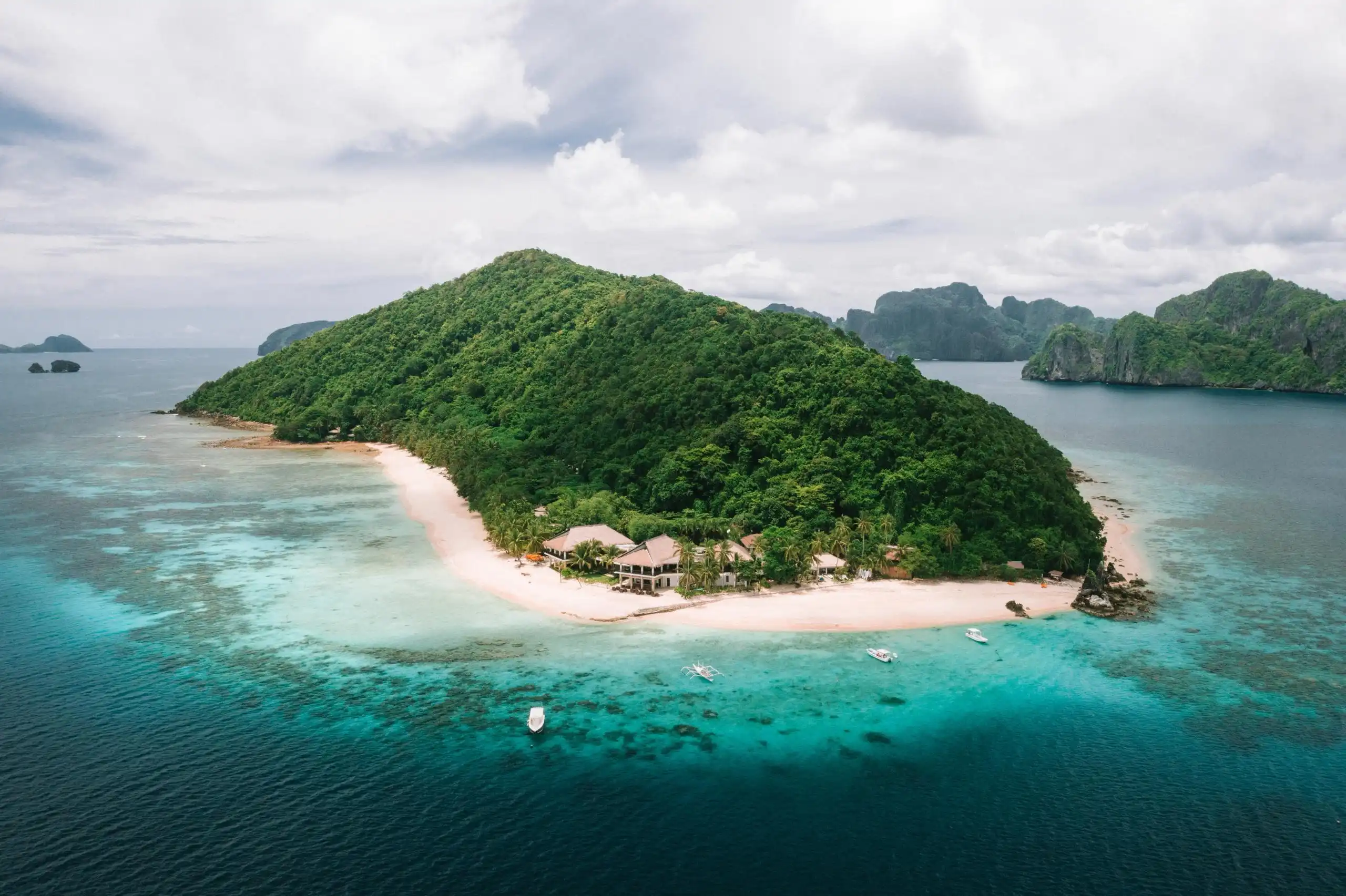 High-angle shot of an exclusive private tropical island resort featuring white sandy beaches and clear turquoise waters in Palawan, Philippines.