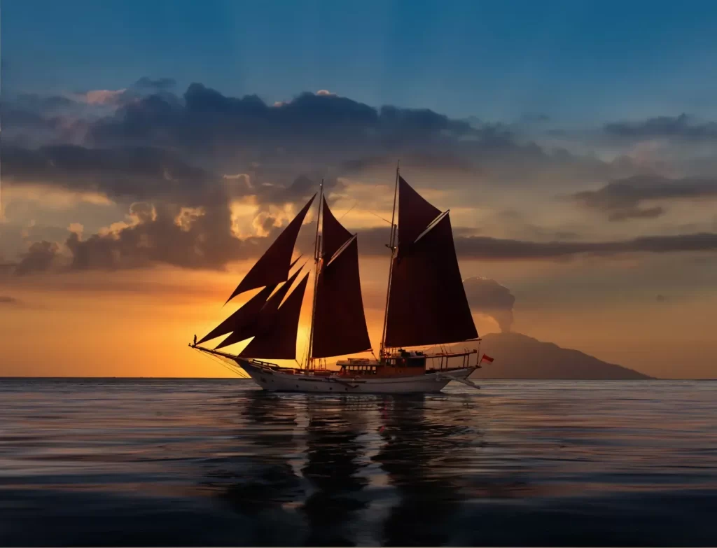 Private phinisi yacht under full sail at sunset in the Indonesian archipelago