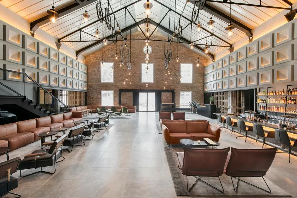 The Warehouse Hotel lobby, an iconic Singapore travel destination, with high ceilings, exposed beams, and stylish leather seating. A key feature for luxury Singapore tours and Singapore holidays.